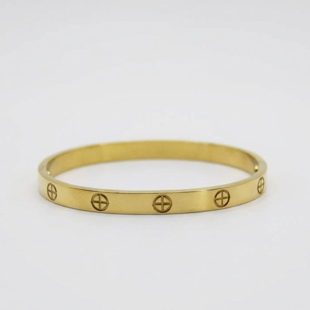 Gold bracelet with engraved symbols on a light gray background