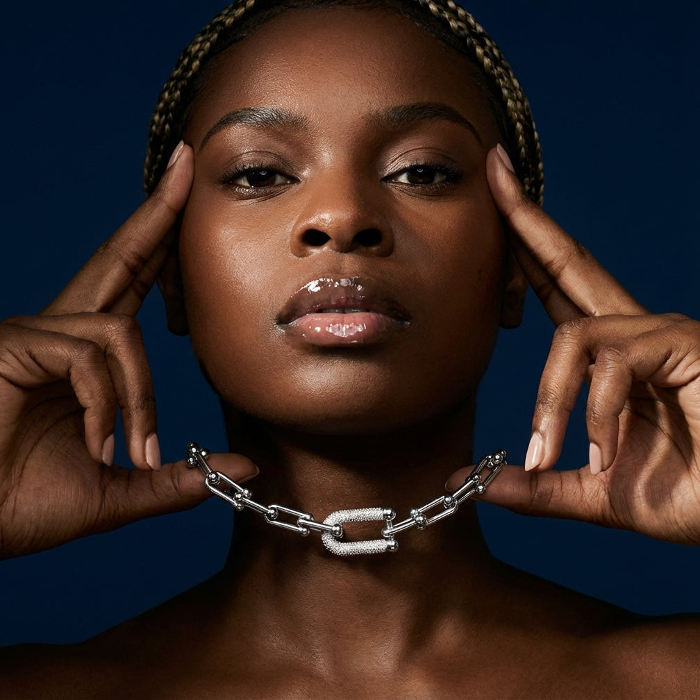 Woman with hands on her head holding a chain against a dark background