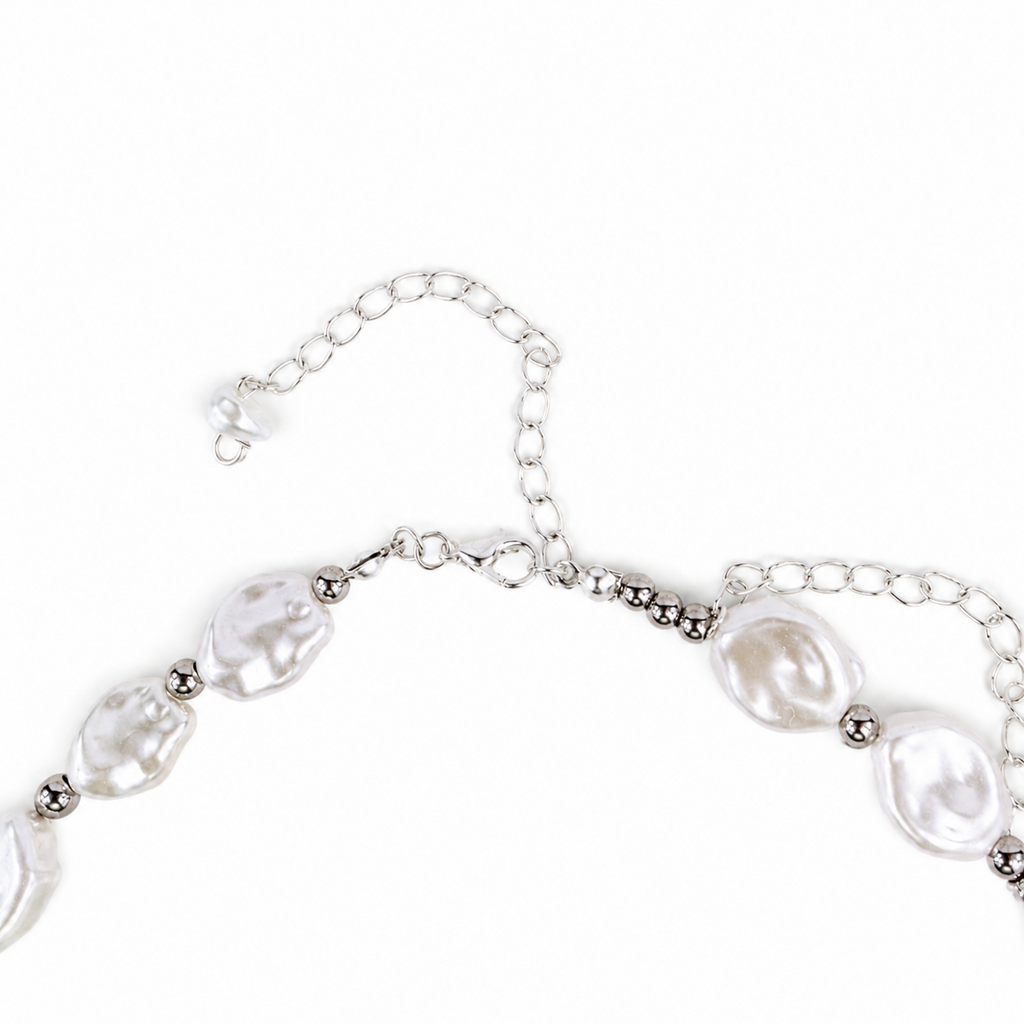A close-up of a silver-toned chain necklace featuring irregular, lustrous white baroque pearls and small metallic spacer beads, shown on a plain white background.