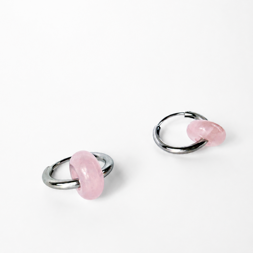 A pair of silver-toned hoop earrings with smooth, polished pink stone accents, displayed on a clean white background.