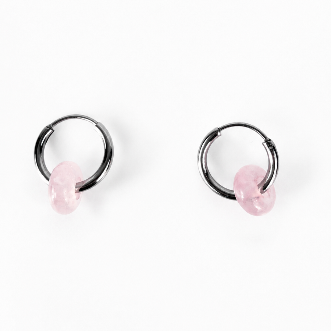 A pair of black metal hoop earrings with small, faceted light pink stone charms, displayed on a clean white background.