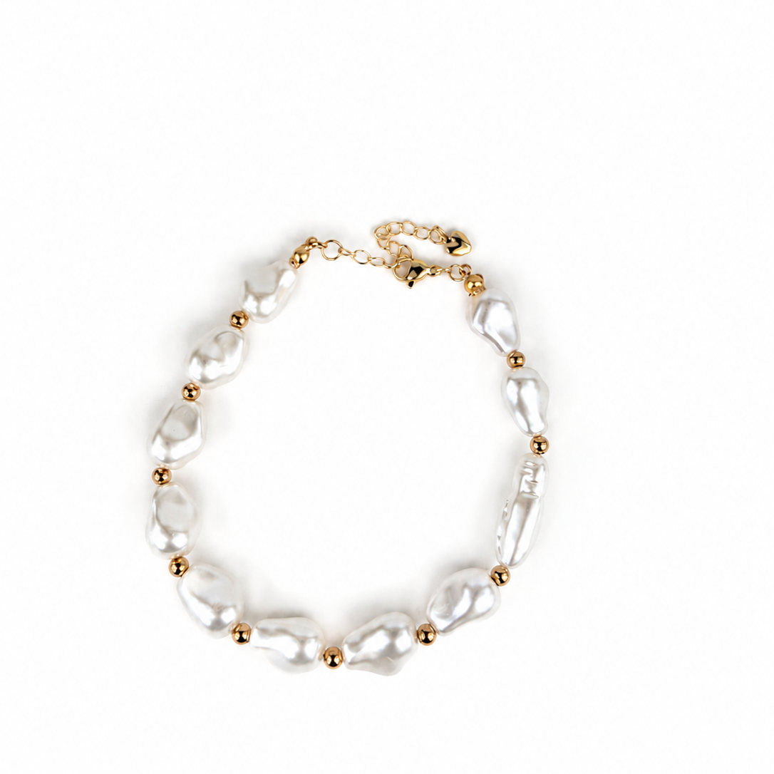 A delicate bracelet featuring irregular white baroque pearls separated by small gold spacer beads and a gold chain extender clasp, displayed on a clean white background.