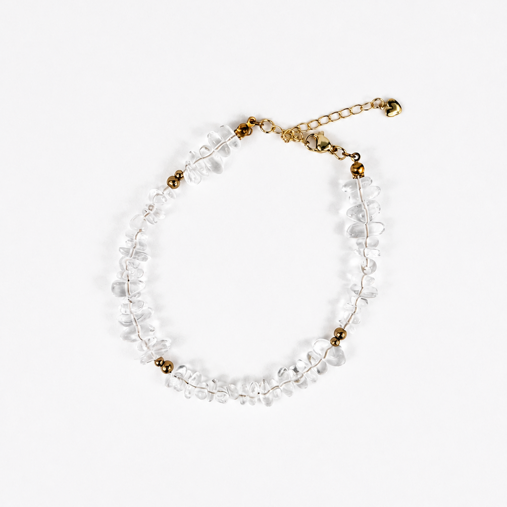A delicate beaded bracelet featuring clear, irregular-cut glass beads strung on a gold-tone wire, accented with small gold beads and a matching gold-tone extender chain with a tiny bell.