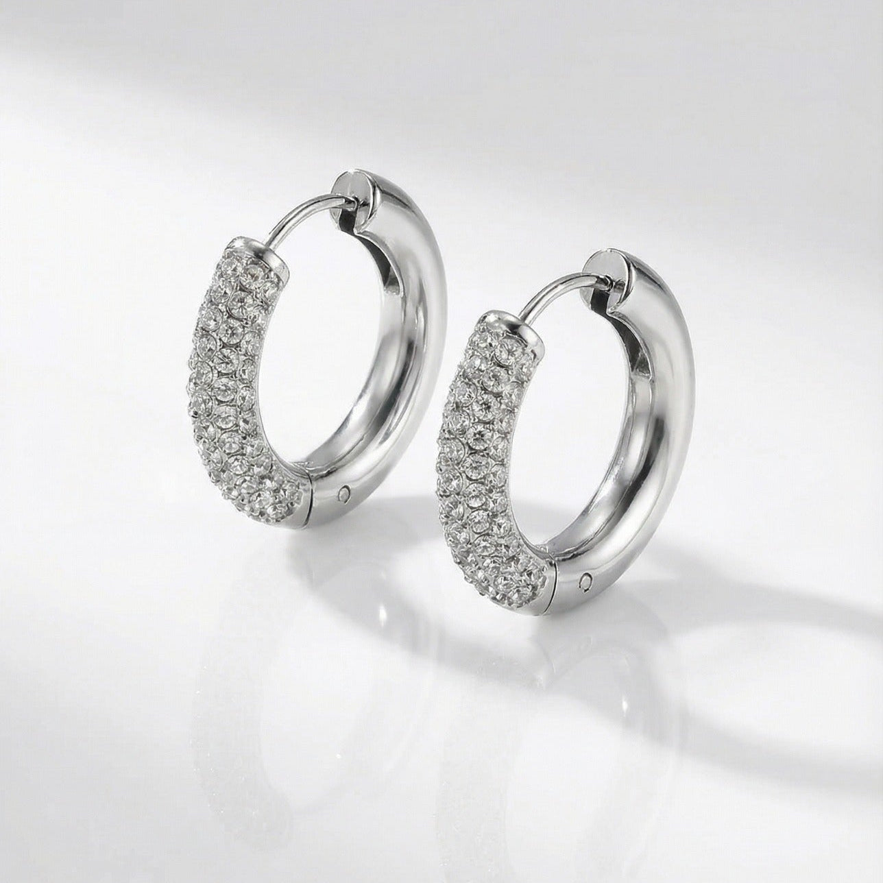 Pair of silver hoop earrings with embedded stones on a light gray background