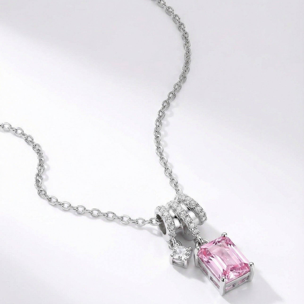 Silver necklace with a pink gemstone pendant on a white background