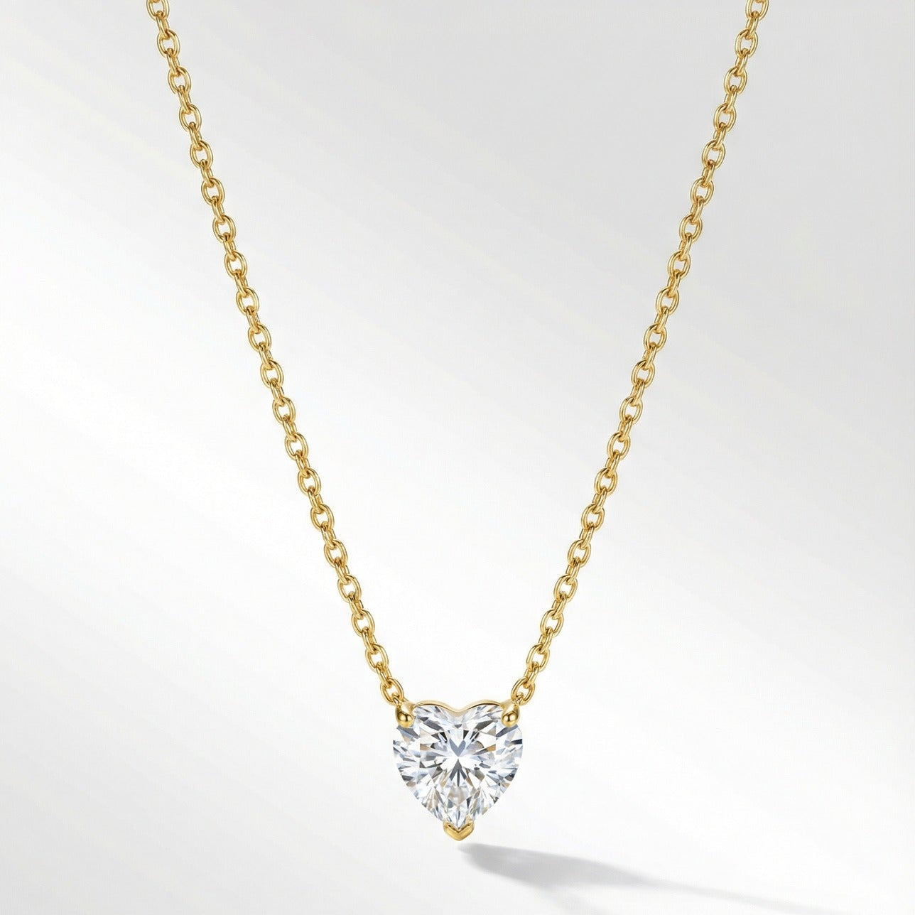 Heart-shaped diamond pendant on a gold chain against a white background