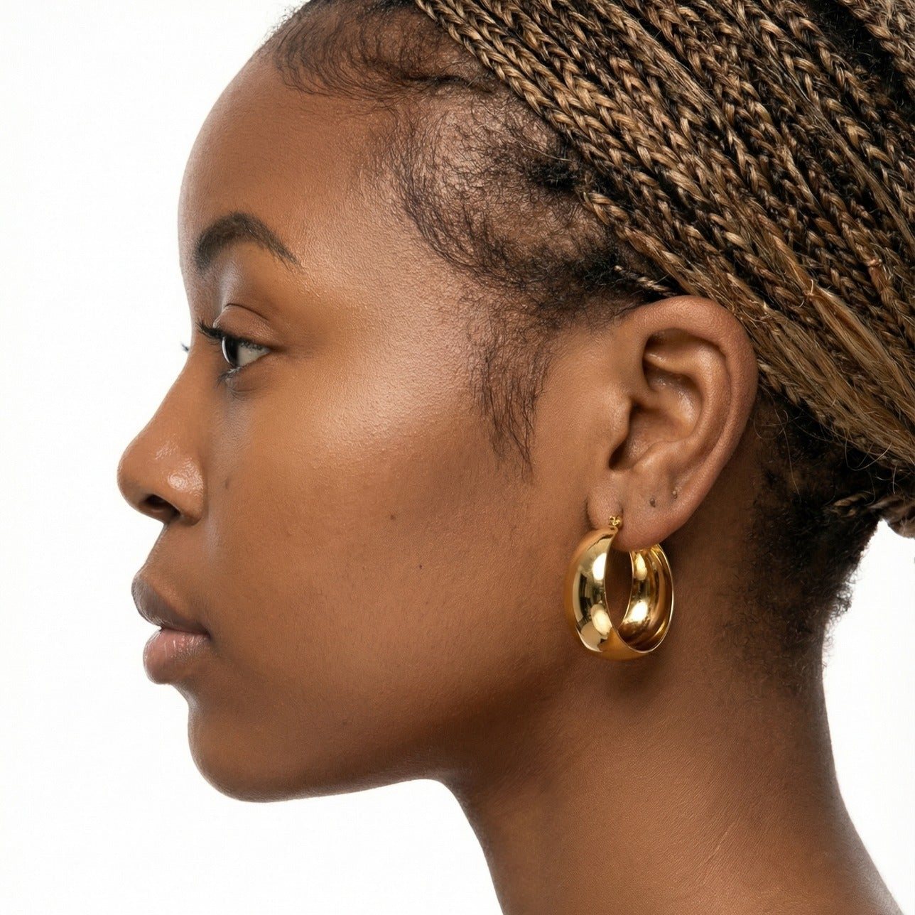 Profile of a woman wearing gold hoop earrings on a white background
