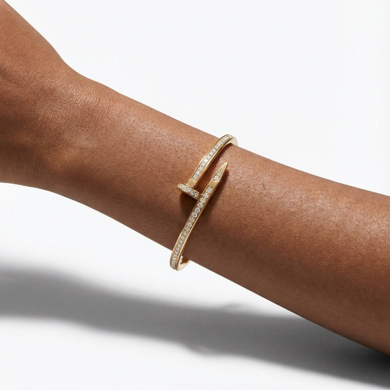 Gold bracelet on a wrist with a white background
