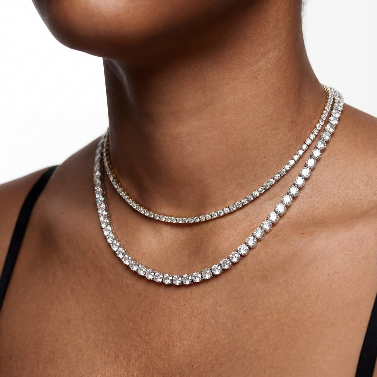 Close-up of a person wearing a sparkling necklace on a plain background