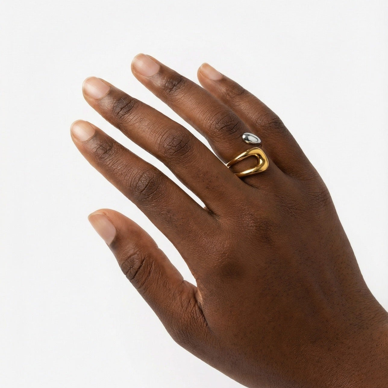 Hand wearing a gold ring with a clear gemstone on a white background