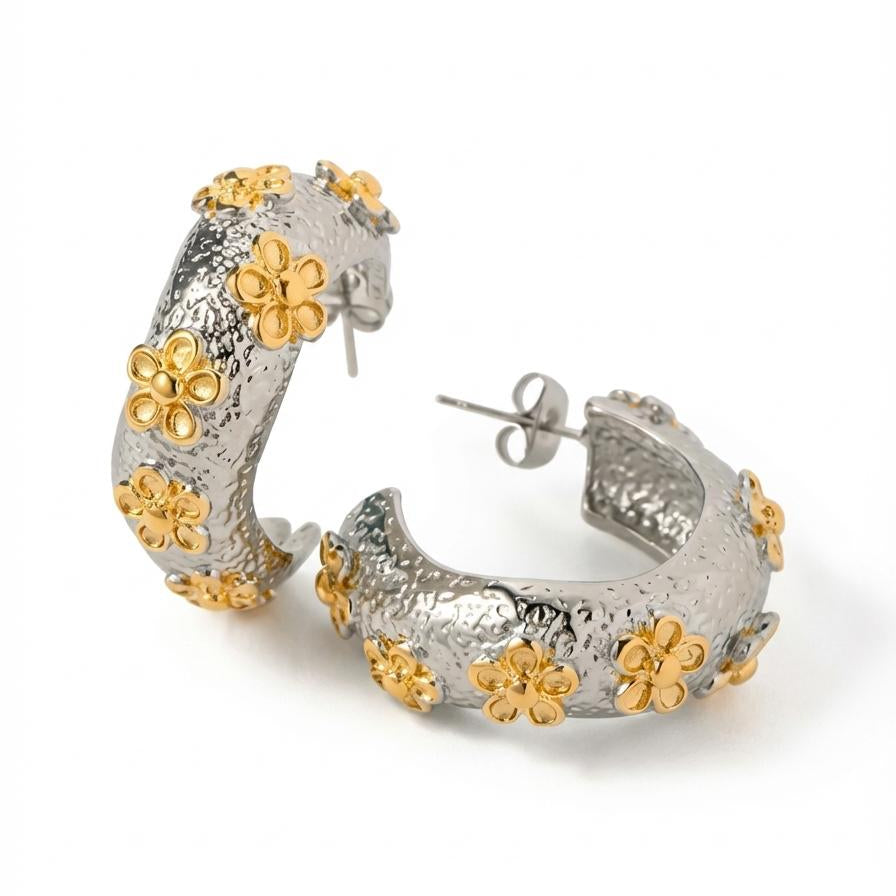 Silver and gold hoop earrings with floral designs on a white background