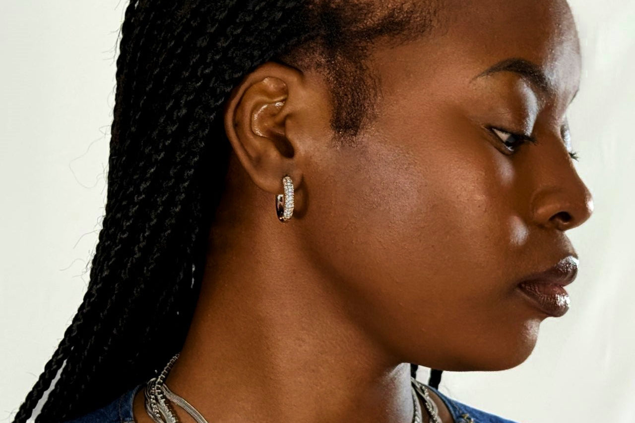 Woman with braided hair wearing diamond earrings on a neutral background