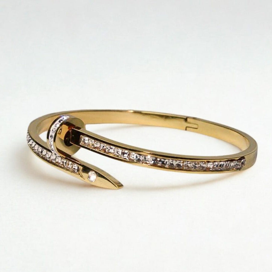 Gold bracelet with small diamonds on a light gray background