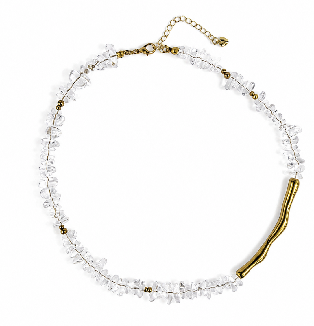 A delicate necklace featuring clear, faceted crystal chips on a thin gold-tone wire, with a wavy gold clasp and an adjustable gold chain extender, displayed on a clean white background.
