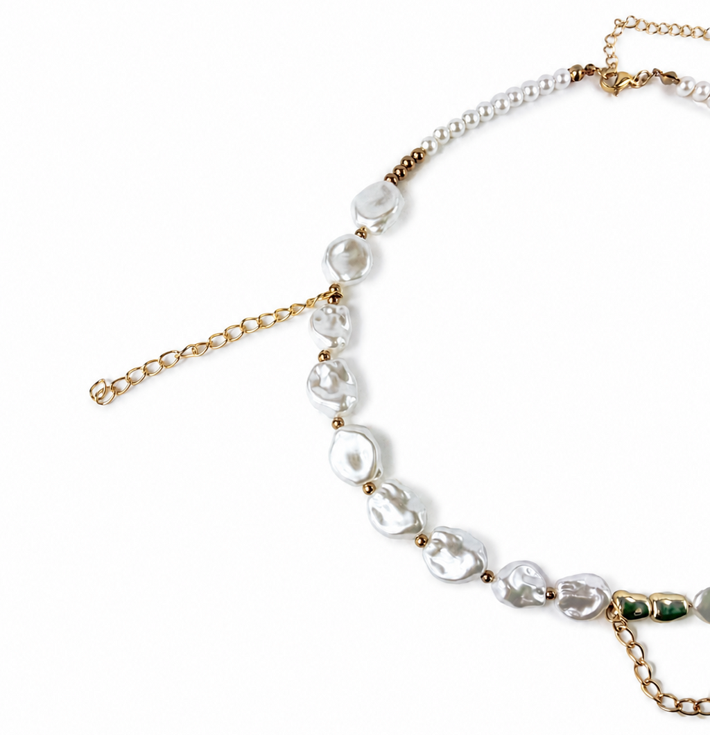 A delicate necklace featuring irregular white baroque pearls and gold-tone chain links, displayed on a clean white background.